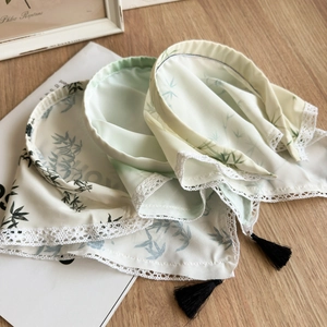 Close-up of silk headscarf with bamboo print, lace edges and elegant black tassels
