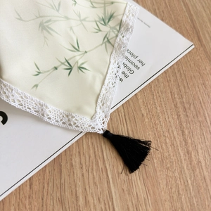 Detailed close-up of a bamboo print silk scarf with white lace edges and a black tassel