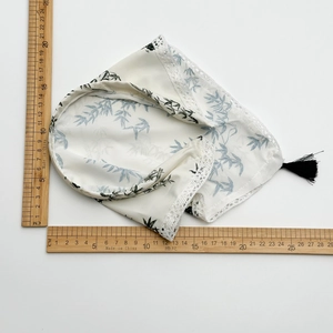Ink bamboo pattern headband with white lace trim and black tassel on a white surface