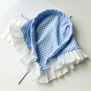 Détails d'un foulard en vichy bleu avec des bords en dentelle blanche à volants