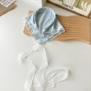 Détail d'un foulard bleu clair à pois avec bordure en dentelle florale blanche et rubans
