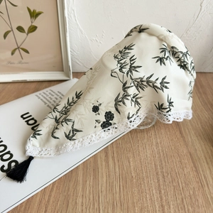 Detail of ink wash floral print on silk-like headband with lace trim and black tassel