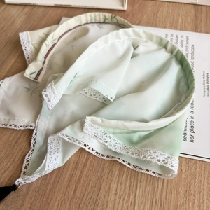 Detail of mint green hair scarf with bamboo patterns, white lace edge and black tassels