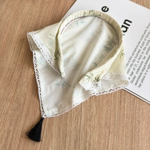 Detail of bamboo leaf print headscarf with delicate white lace trim and black tassel