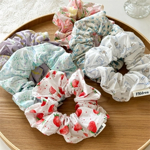 Detailed macro view of assorted floral fabric scrunchies on a wooden tray with FMdrea tag