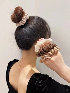 Gros plan de chouchous en satin de soie beige et marron sur les cheveux d'un modèle