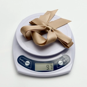 Détail du nœud en satin champagne léger de 9,7g présenté sur une balance électronique