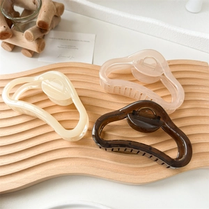 Three large jelly-colored cloud hair claws in cream, pink, and amber on a wooden display