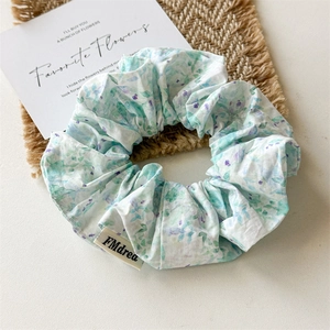 Detailed macro view of floral fabric scrunchie with light green and purple patterns