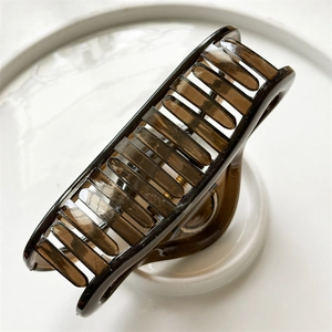 Detail view of large dark brown jelly hair claw clip on a white decorative plate