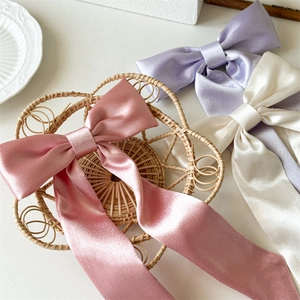 Dettaglio di eleganti fiocchi per capelli in raso rosa, lavanda e crema con nastri lunghi
