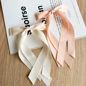 Détail de barrettes à nœuds en ruban de satin double couche en beige et rose élégant