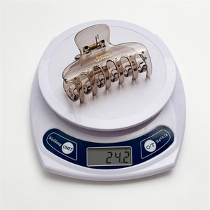Detailed weight display of brown resin claw clip with gold lettering on a digital scale