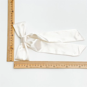 Dettaglio del fiocco per capelli in raso bianco con nastri lunghi e seta liscio