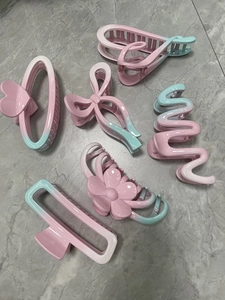Detailed set of six matte pink and blue gradient hair claws in various flower and geometric shapes