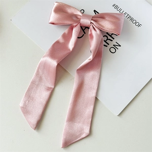 Dettaglio del fiocco in raso rosa con nastri lunghi e consistenza del tessuto liscia e lucida