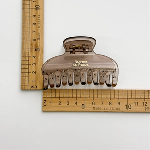 Minimalist brown resin hair claw clip with gold lettering measuring 8.5cm long