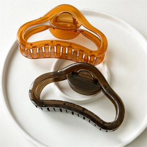 Close-up of large wavy hair claws in amber and coffee colors on a white ceramic plate