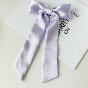 Dettaglio del grande fiocco per capelli in raso lavanda con texture liscia e lucentezza