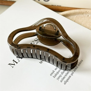 Macro detail of wave-shaped translucent brown hair claw clip with durable metal spring