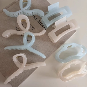 Detailed view of seven matte resin hair claws in light blue and beige neutral tones