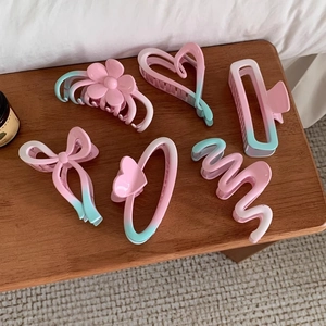Detail of 6-piece pink and mint green gradient hair claws on a rustic wooden table