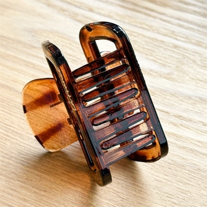 Detailed macro view of glossy amber tortoise resin hair claw with La France gold lettering