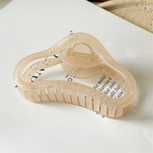 Close-up of cream translucent acrylic hair claw clip with wavy edges on white background