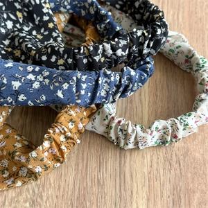 Floral print elastic headbands set in black, navy, yellow and white on a wood surface