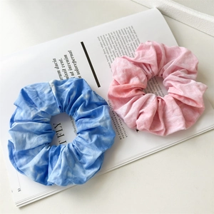 Detailed view of pink and blue tie-dye fabric scrunchies on a minimalist background
