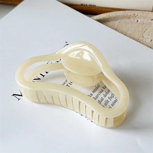 Macro shot of large cream jelly-colored curved claw clip on a minimalist magazine