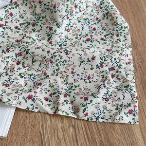 Close-up of floral print fabric with pink flowers and green leaves on wooden table