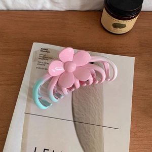 Pink and blue gradient flower hair claw clip displayed on an artistic magazine cover