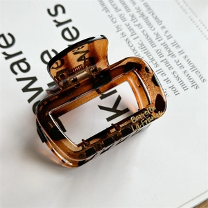 Detailed view of square amber resin hair claw with gold lettering and sturdy metal spring