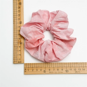 Pink tie-dye fabric scrunchie made of washed cotton, measuring 10cm on a white background