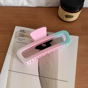 Close-up of a matte rectangle hair claw clip with pink and blue gradient on a magazine
