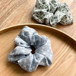 Nahaufnahme von Blumen-Haargummis aus Stoff in Blau und Weiß auf einem Holztablett