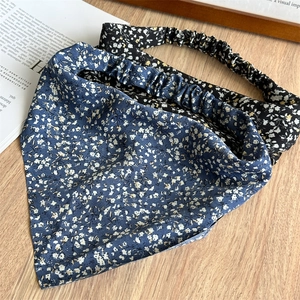 Close-up of floral print elastic bandanas in navy and black on a rustic wooden desk