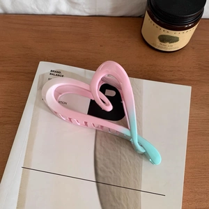 Detail of pink and blue gradient heart hair claw clip on a stylish magazine background