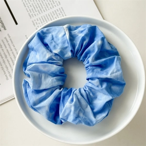 Detail of blue and white tie-dye scrunchie with soft cotton texture in a ceramic dish