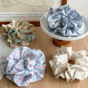Floral and plaid oversized fabric hair scrunchies on a minimalist display stand