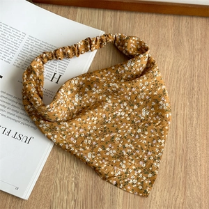Detail of floral head scarf in mustard yellow with elastic band on wooden table