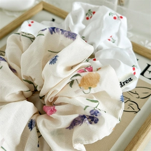 Detail of floral scrunchies with cherry and purple flower patterns on soft chiffon fabric