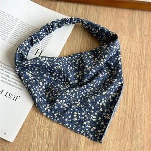 Detail of navy blue floral triangle headscarf with elastic band on wooden table