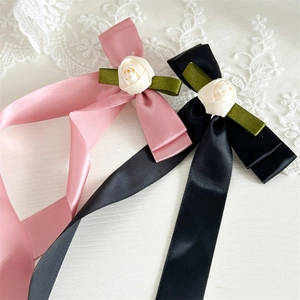 Detail of elegant satin bow hair clips with rose floral accent in pink and black