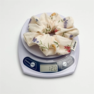 Detail shot of lightweight floral hair scrunchie weighing 12 grams on digital scale