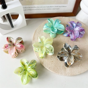 Detailed close-up of colorful flower hair claws with marble texture on stone display