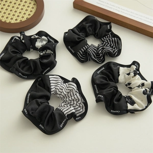 Set of four black and white scrunchies with CHANGE lettering in a lifestyle flat lay