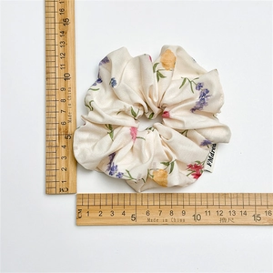 Floral print oversized scrunchie in beige fabric shown with a ruler for size scale