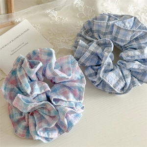 Detailed view of handmade pink and blue plaid cotton scrunchies on white lace